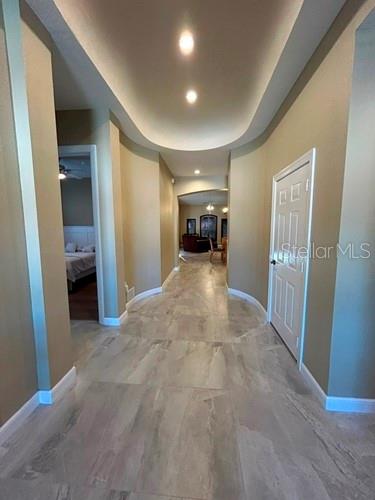 A hallway with light-colored tile flooring leads toward a living area with arched entryways — 5461 46TH COURT W, BRADENTON, FL