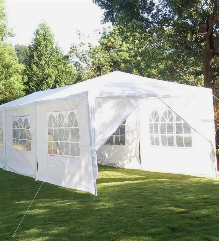 A large white party tent with arched windows stands on a grassy lawn — 7022 RIVERSIDE DRIVE, PUNTA GORDA, FL
