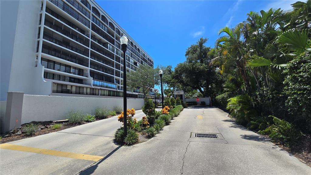A paved driveway leads toward a gated entrance beside a multi-story residential building — 3211 W SWANN AVENUE UNIT 1110, TAMPA, FL