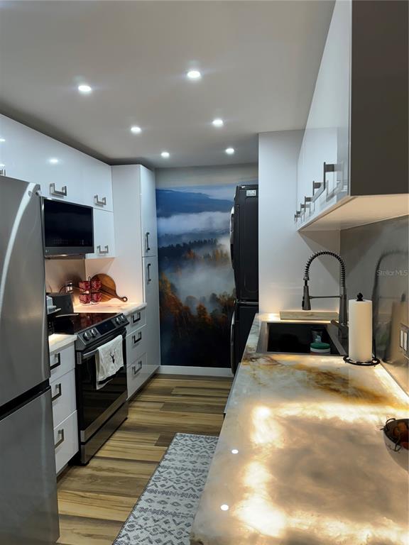 A modern kitchen features white cabinetry, a backlit stone countertop, and a mountain landscape mural — 3211 W SWANN AVENUE UNIT 1110, TAMPA, FL