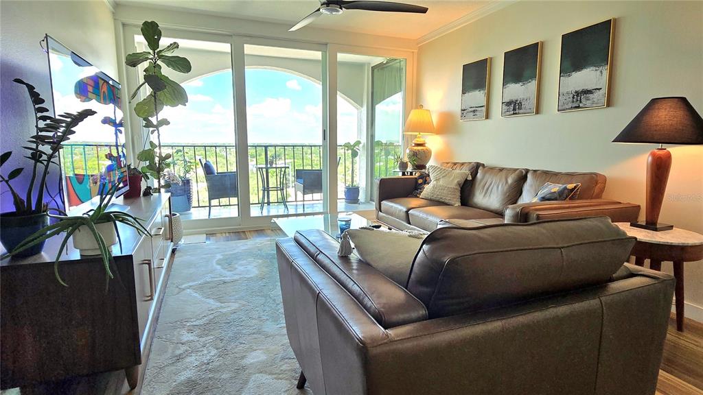 A living room features a television, leather furniture, a ceiling fan, and a balcony view — 3211 W SWANN AVENUE UNIT 1110, TAMPA, FL
