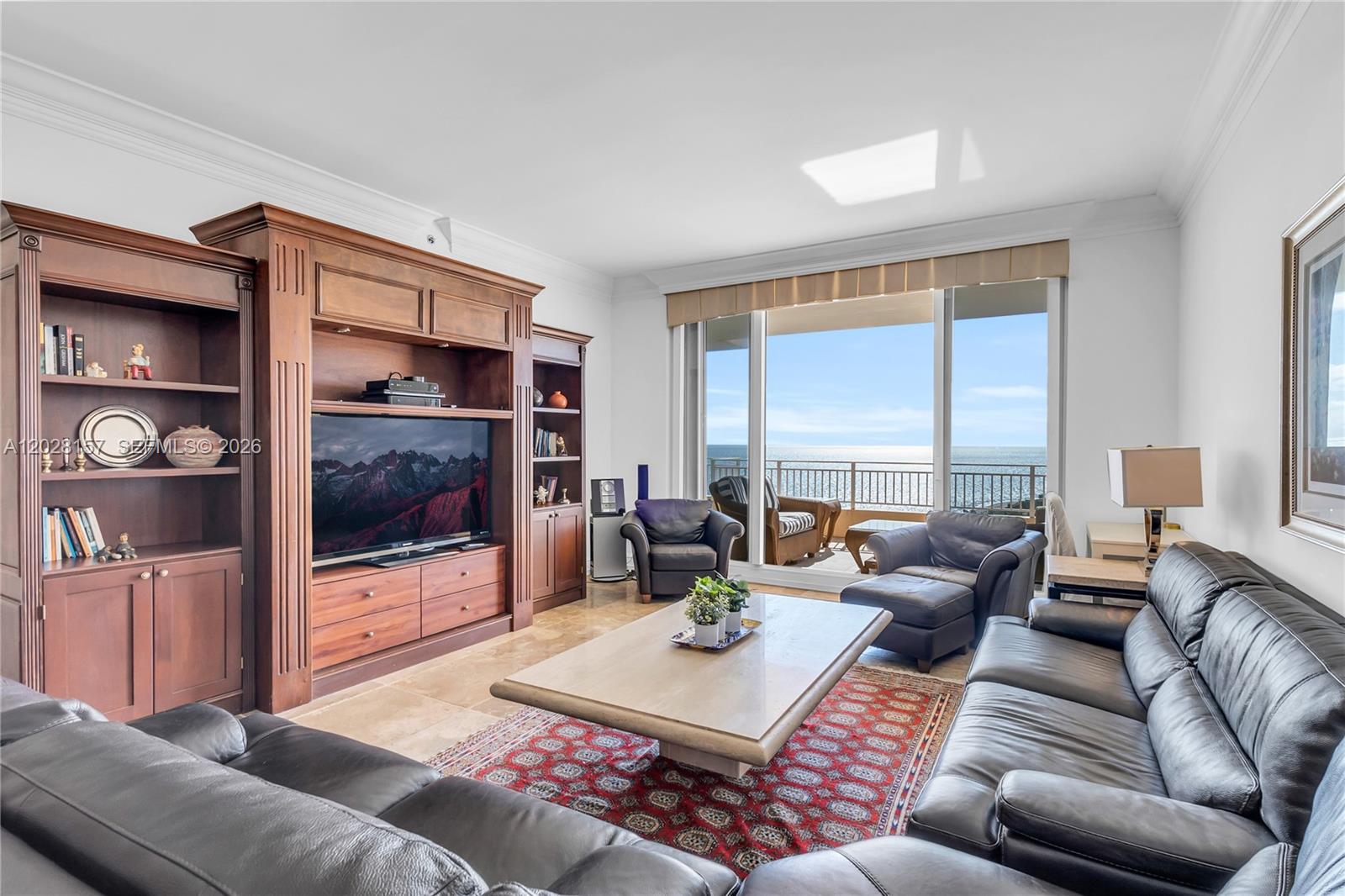 A living room features leather sofas, a large wooden entertainment center, and a balcony overlooking the ocean — 791 Crandon Blvd, Key Biscayne FL 33149, KEY BISCAYNE, FL