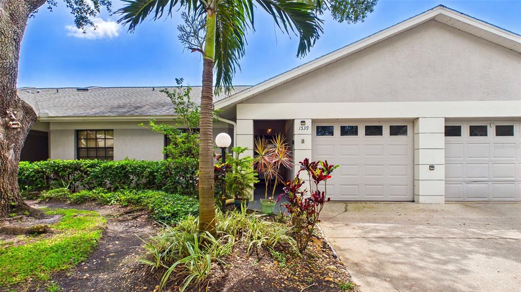 The exterior view shows a single-story home with a two-car garage and landscaped front yard — 1539 REBECCA LANE, DUNEDIN, FL