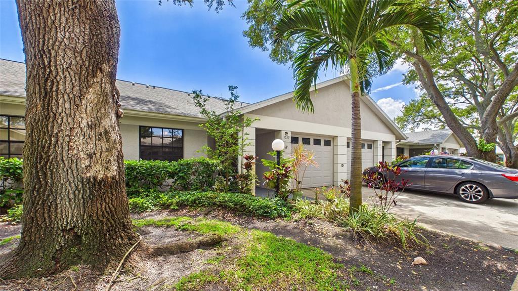 A gray sedan is parked in the driveway of a single-story home with a garage — 1539 REBECCA LANE, DUNEDIN, FL