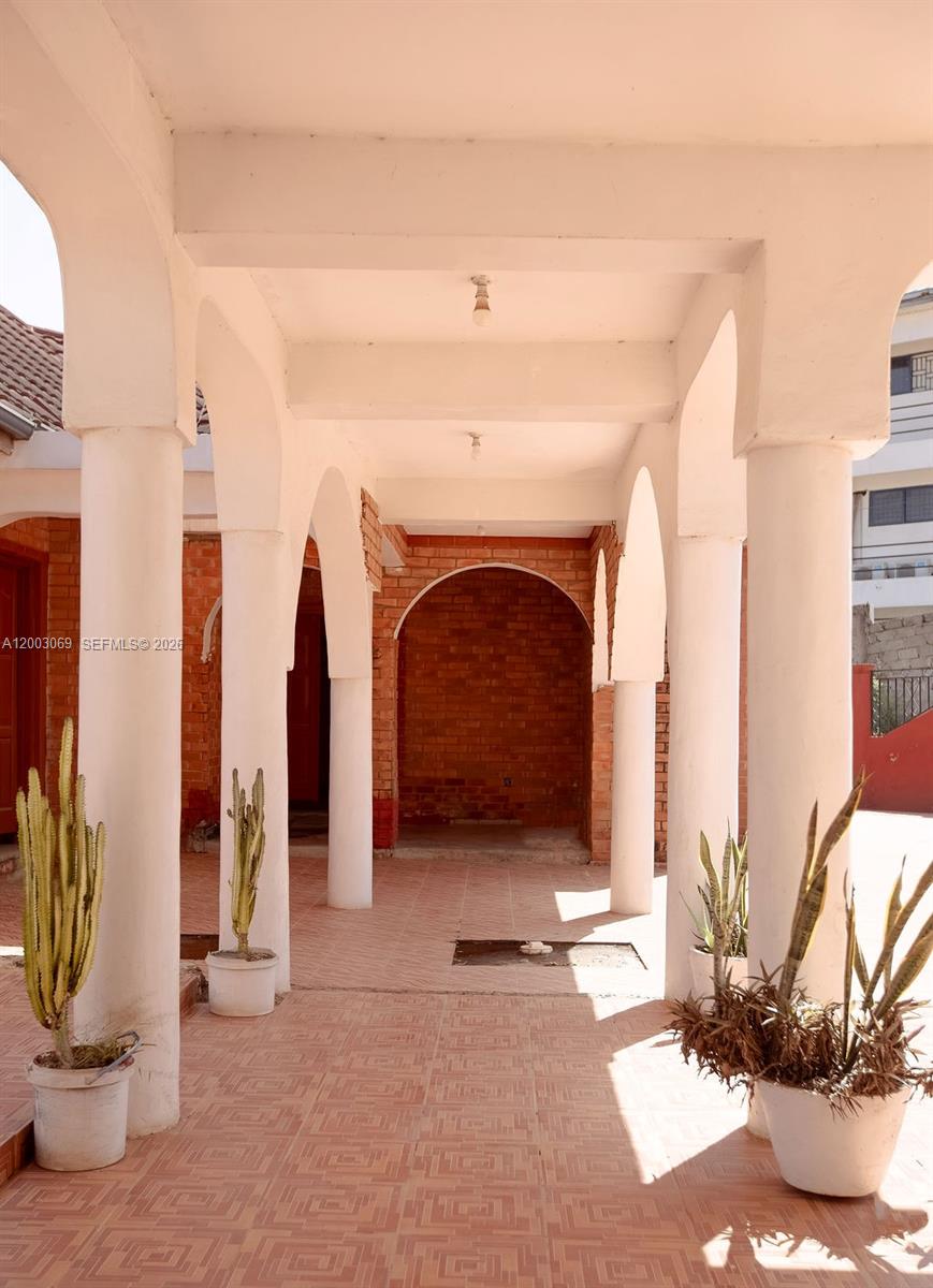 A covered outdoor patio features brick walls, tiled floors, and several white support columns — 72 Nmai Dzorn Adjiringano Road, FL