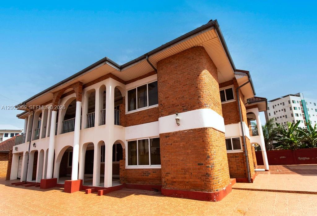 A two-story brick building with white arched columns and a tiled patio area — 72 Nmai Dzorn Adjiringano Road, FL