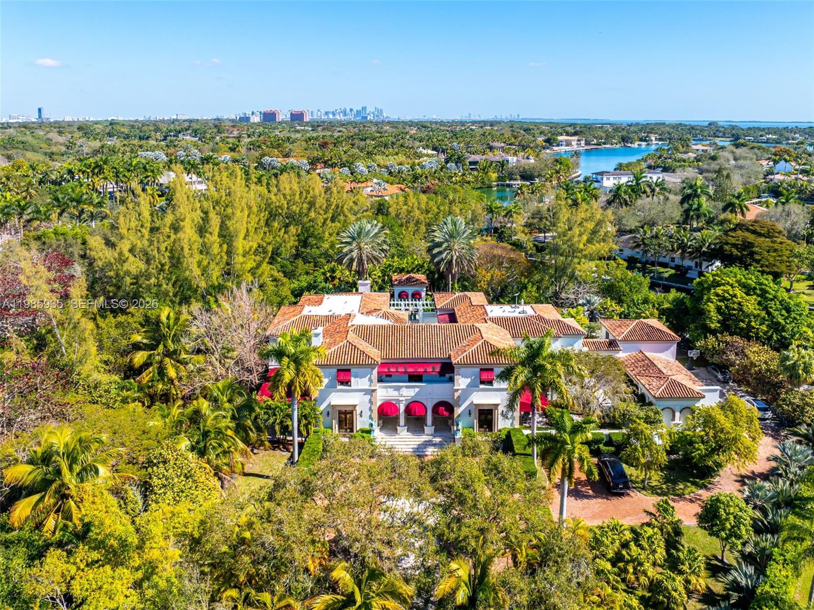 An aerial view of a large Mediterranean-style mansion surrounded by lush tropical landscaping — 9401 Journeys End Rd, Coral Gables FL 33156, CORAL GABLES, FL