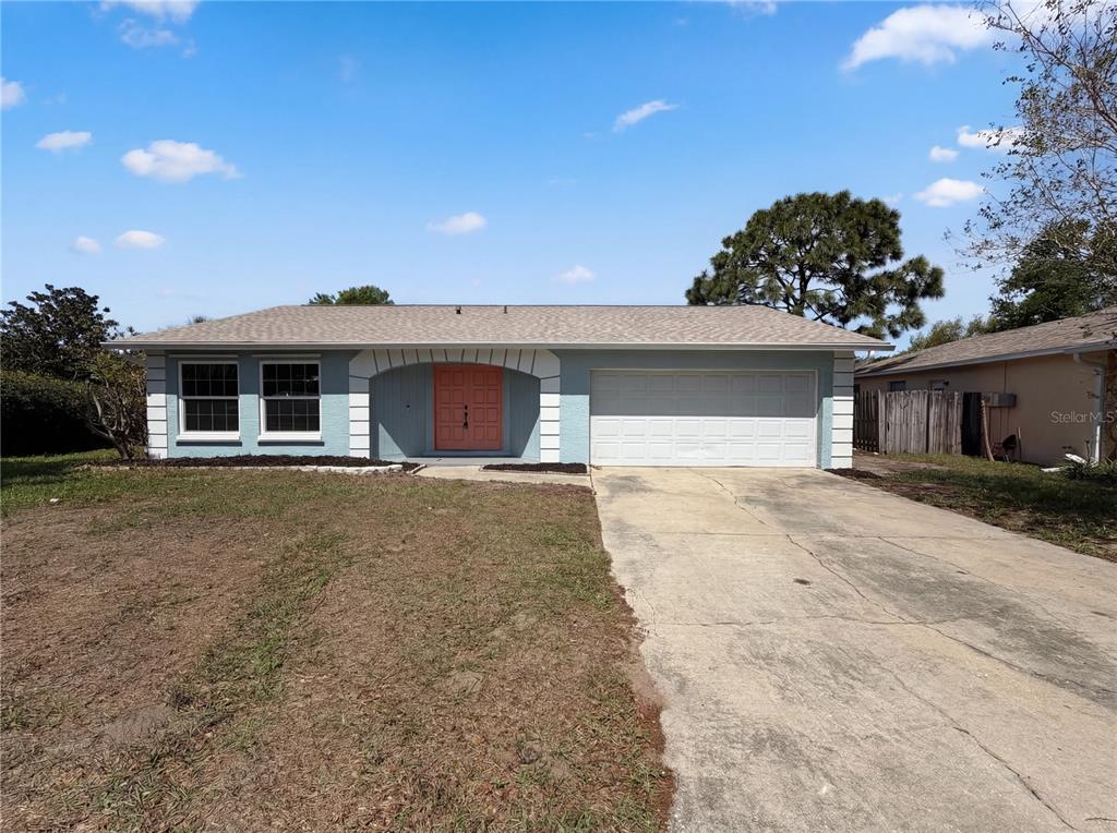 A single-story house with a light blue exterior, white trim, and a coral-colored front door — 1512 CASCADE COURT, DUNEDIN, FL