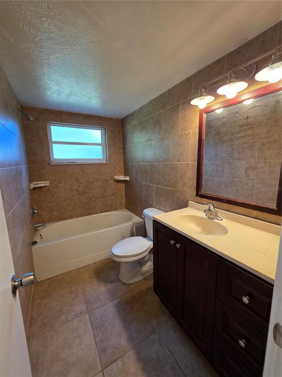 A bathroom features a tub-shower combination, a toilet, and a vanity with a dark cabinet — 219 HAYS DRIVE, SANFORD, FL