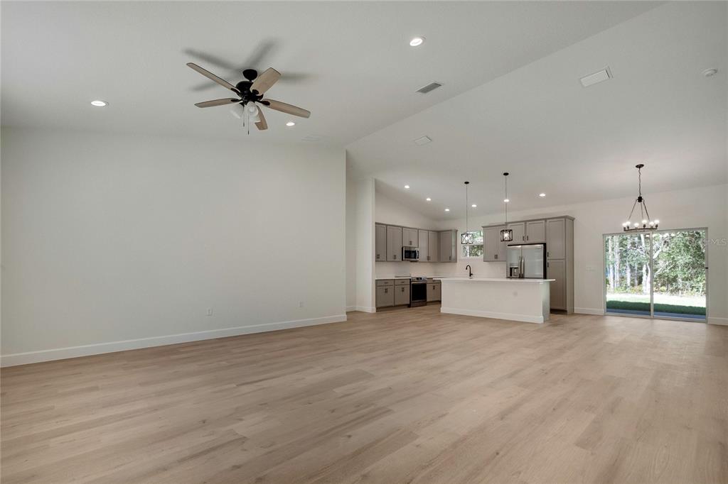 An open-concept living area with light wood flooring, a ceiling fan, and a modern kitchen — 8104 N SANTOS DRIVE, CITRUS SPRINGS, FL