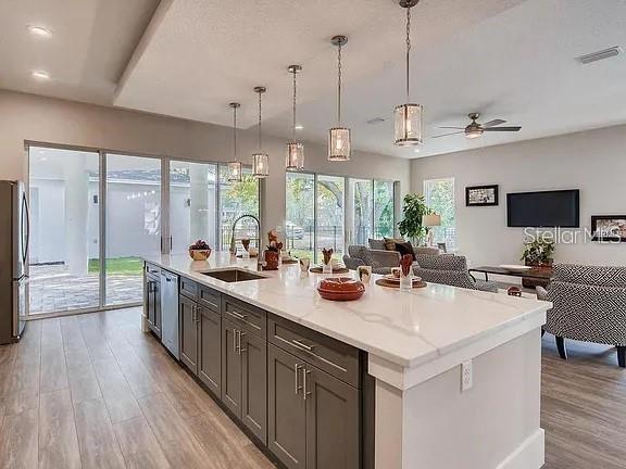 A modern kitchen features a large white marble island, gray cabinetry, and stainless steel appliances — 200 E GRANT STREET, ORLANDO, FL