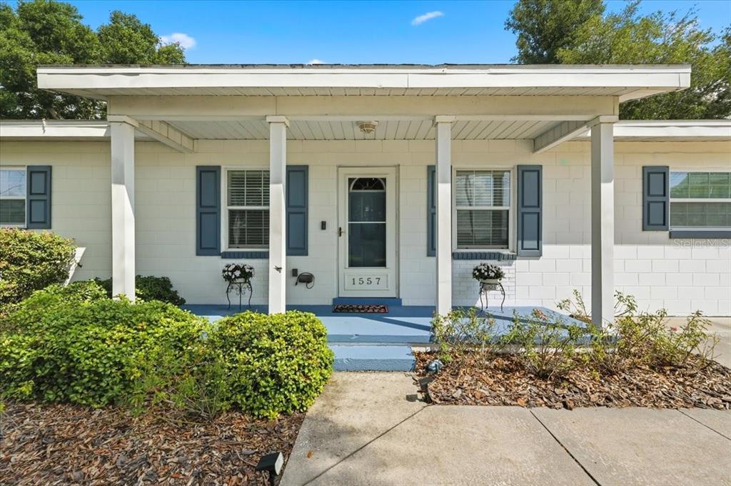 The exterior of a single-story house features a covered porch with white columns and shutters — 1557 N LAKE SHIPP DRIVE SW, WINTER HAVEN, FL