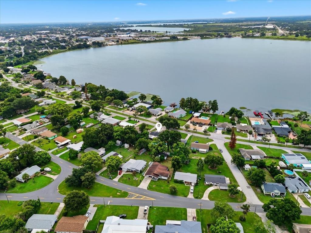 An aerial view shows a residential neighborhood situated along the shore of a large lake — 1557 N LAKE SHIPP DRIVE SW, WINTER HAVEN, FL
