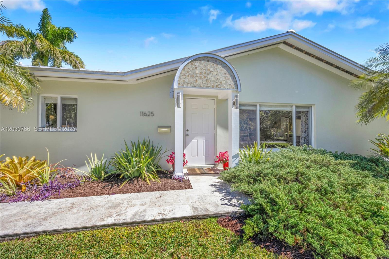The exterior of a light-colored house features a white front door under a tiled archway — 11625 SW 70th Ave, Pinecrest FL 33156, PINECREST, FL