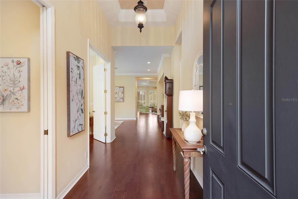 A view from an open front door into a hallway with hardwood floors and artwork — 7241 ORCHID ISLAND PLACE, BRADENTON, FL