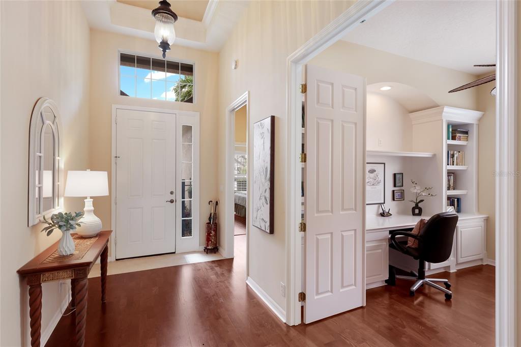 A foyer with hardwood floors leads to a home office with built-in shelving and desks — 7241 ORCHID ISLAND PLACE, BRADENTON, FL