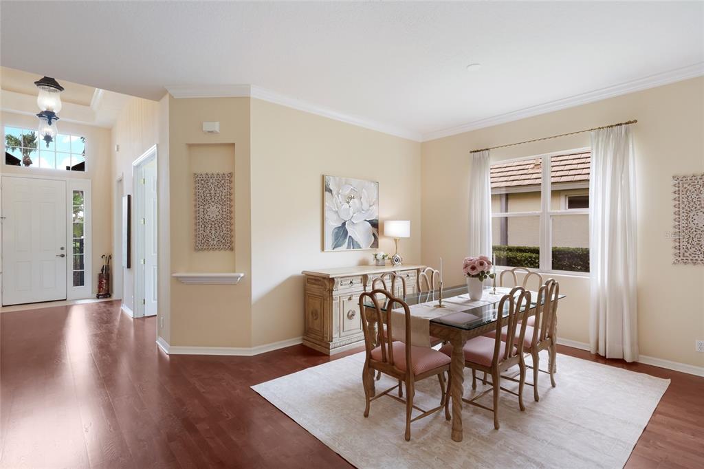 A dining room features a glass-top table, wooden chairs, a sideboard, and hardwood floors — 7241 ORCHID ISLAND PLACE, BRADENTON, FL