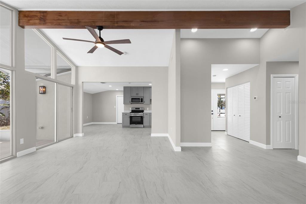 A bright kitchen and dining area with gray cabinets, light wood-look flooring, and sliding doors — 729 SPANISH MAIN DRIVE, APOLLO BEACH, FL