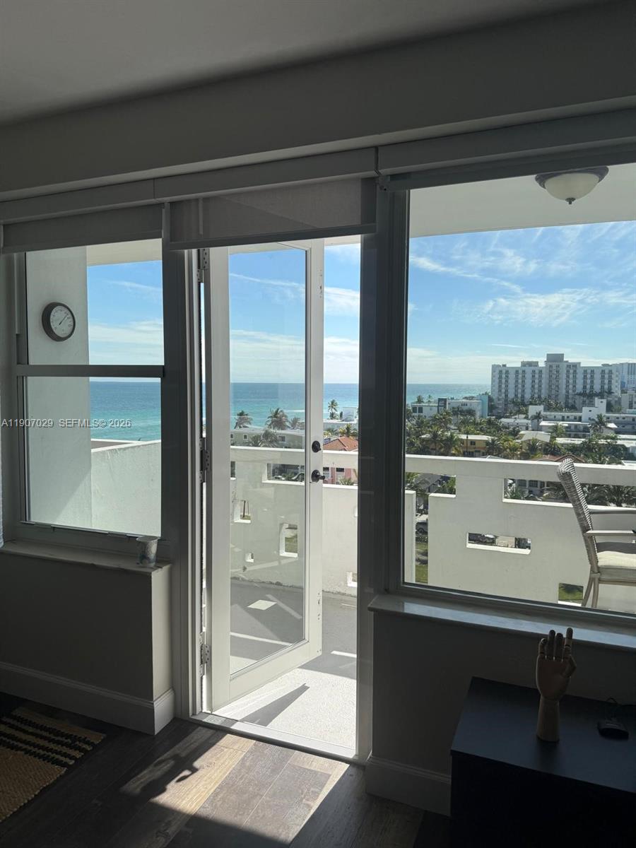 A room with a glass door opens onto a balcony overlooking the ocean and buildings — 3111 N Ocean Dr # 811, Hollywood FL 33019, HOLLYWOOD, FL