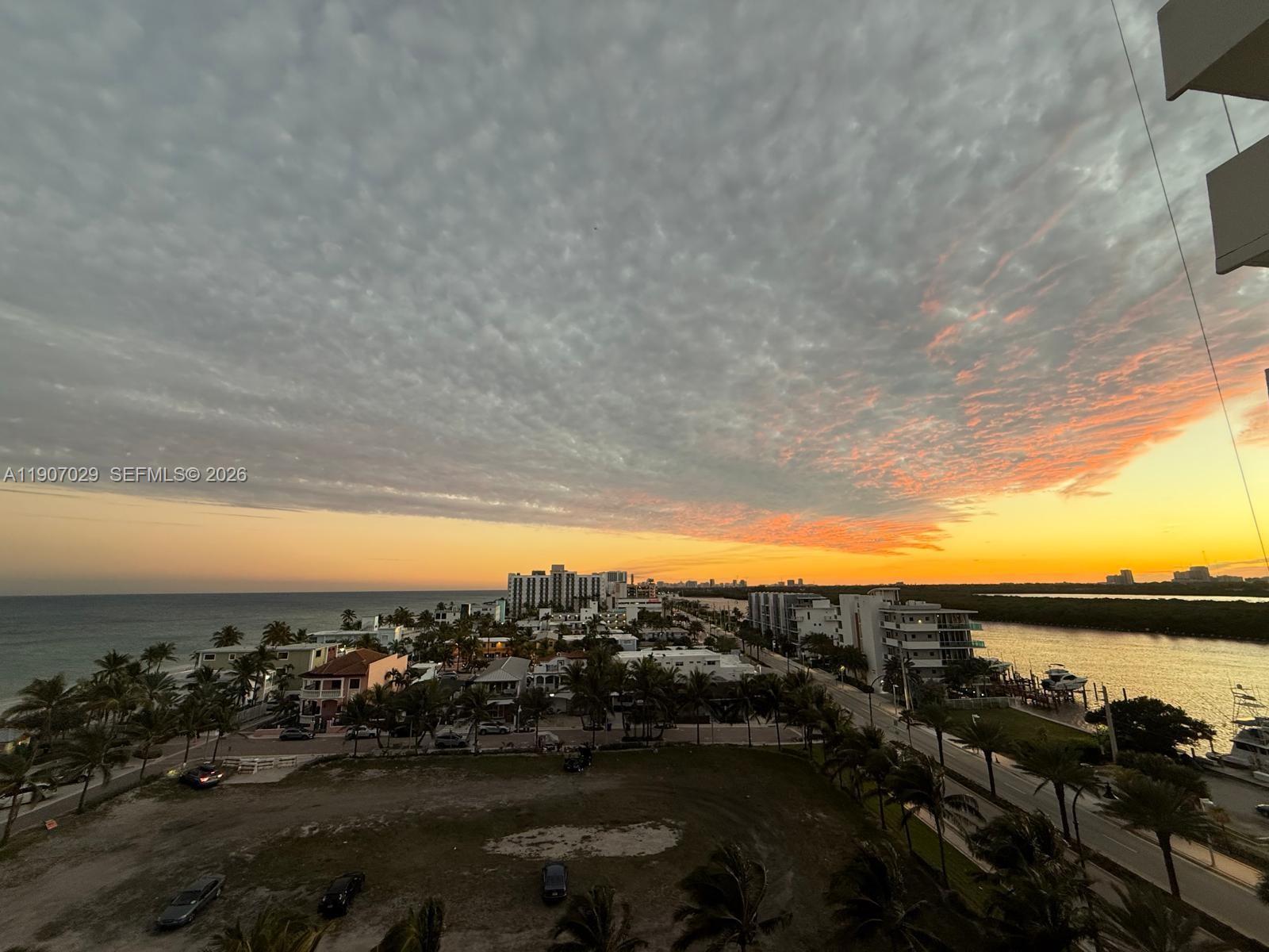 An elevated view of a coastal town at sunset with buildings, palm trees, and water — 3111 N Ocean Dr # 811, Hollywood FL 33019, HOLLYWOOD, FL