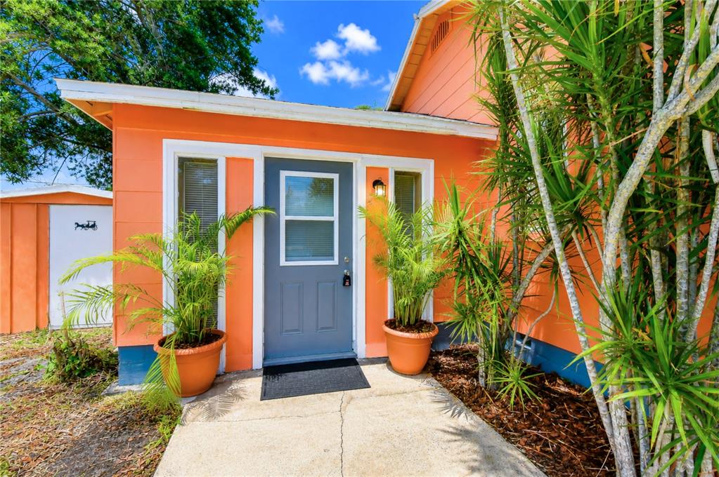 An orange house exterior features a grey front door flanked by two potted palm plants — 5509 15TH AVENUE S, GULFPORT, FL
