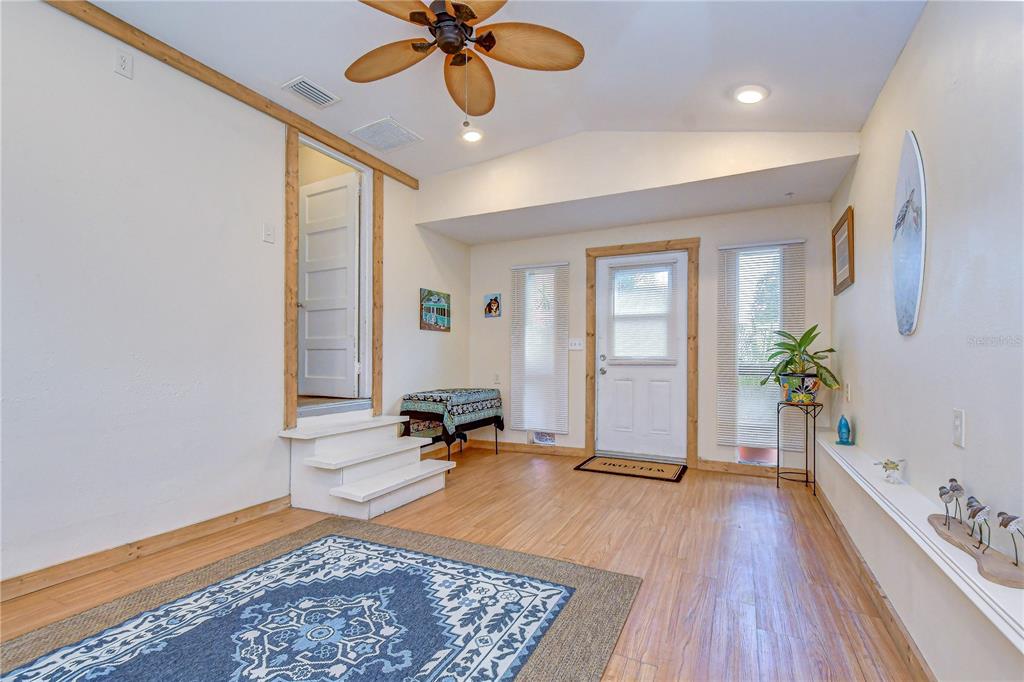A sunroom features wood-look flooring, a vaulted ceiling with a fan, and a raised doorway — 5509 15TH AVENUE S, GULFPORT, FL