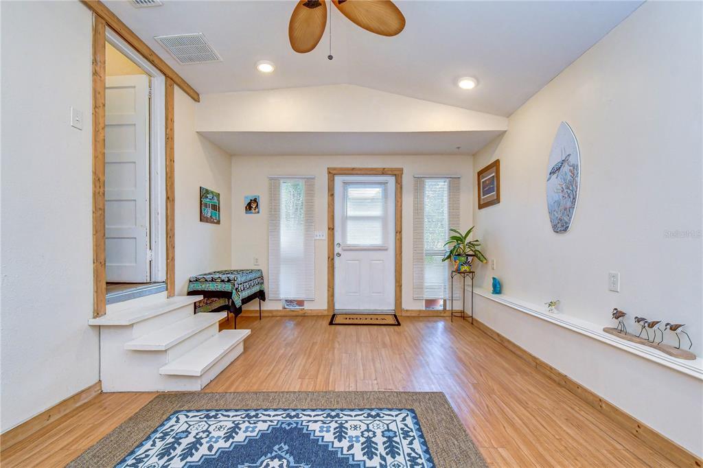 A bright room with wood flooring, a vaulted ceiling, white steps, and a central door — 5509 15TH AVENUE S, GULFPORT, FL
