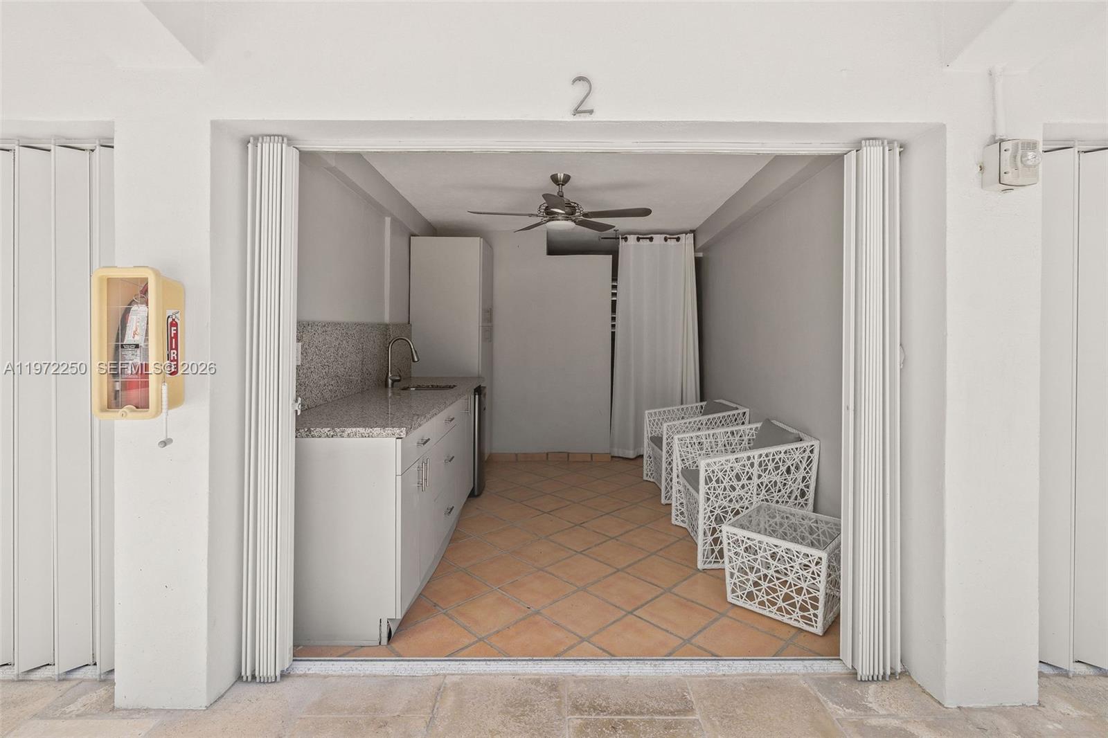 A covered outdoor patio features a kitchenette with granite countertops, tile flooring, and white furniture — 4925 Collins Ave, Miami Beach FL 33140, MIAMI BEACH, FL
