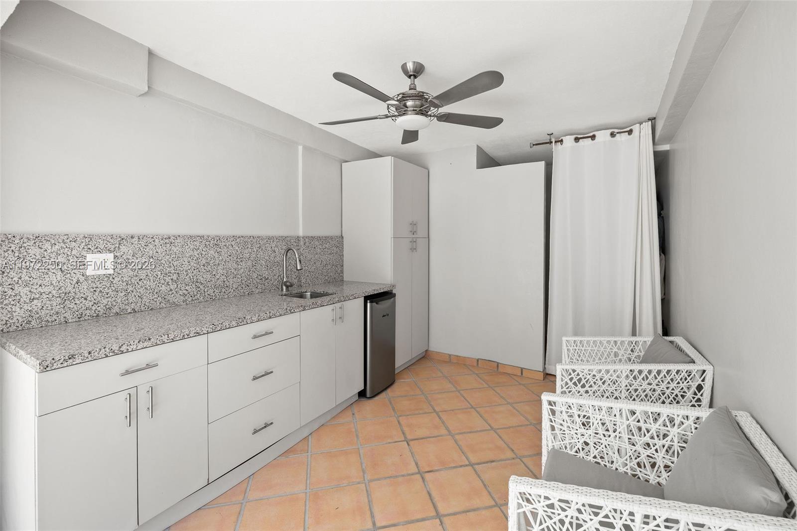 A small kitchen area features white cabinets, granite countertops, tile flooring, and two wicker chairs — 4925 Collins Ave, Miami Beach FL 33140, MIAMI BEACH, FL