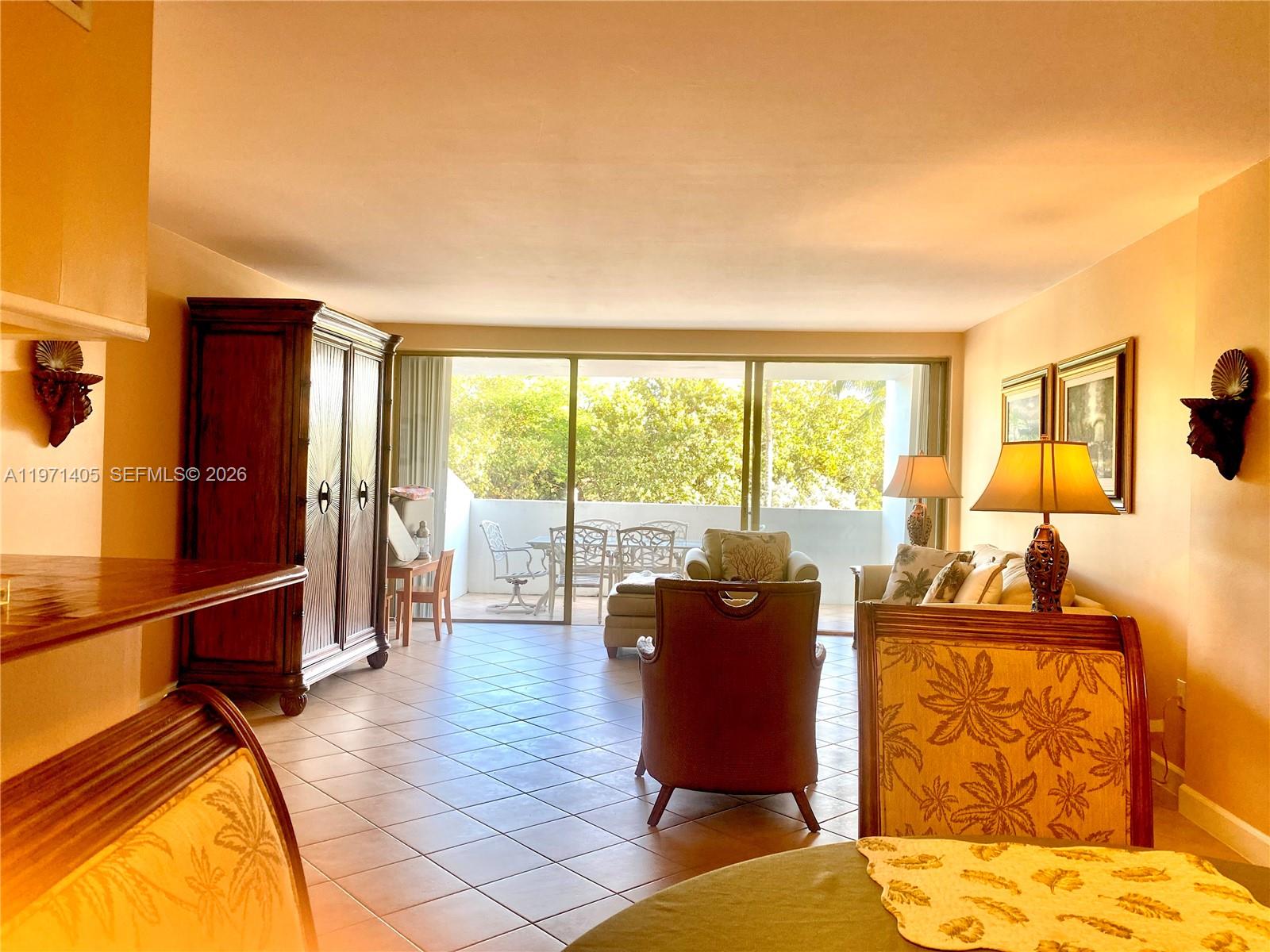 A living room features tile floors, a large armoire, and a balcony with outdoor seating — 177 Ocean Lane Dr # 204, Key Biscayne FL 33149, KEY BISCAYNE, FL