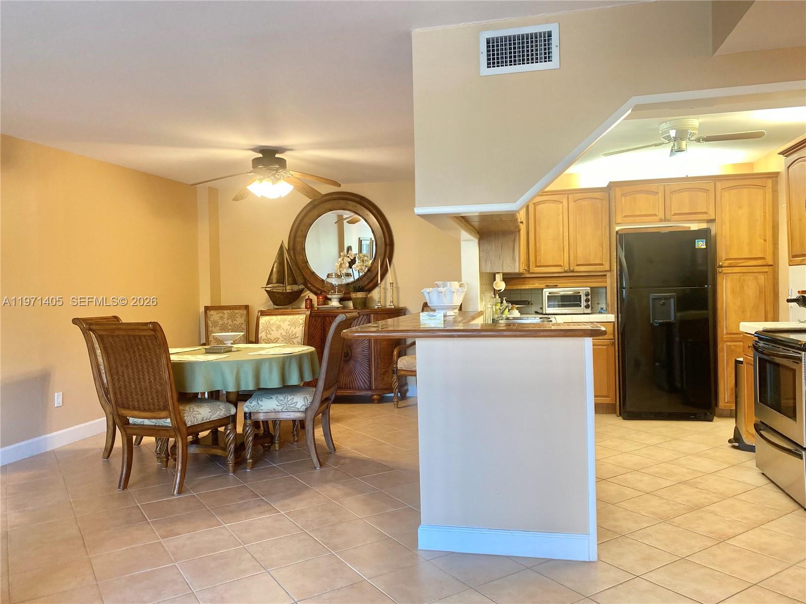 A dining area with a round table sits adjacent to a kitchen with wooden cabinets — 177 Ocean Lane Dr # 204, Key Biscayne FL 33149, KEY BISCAYNE, FL