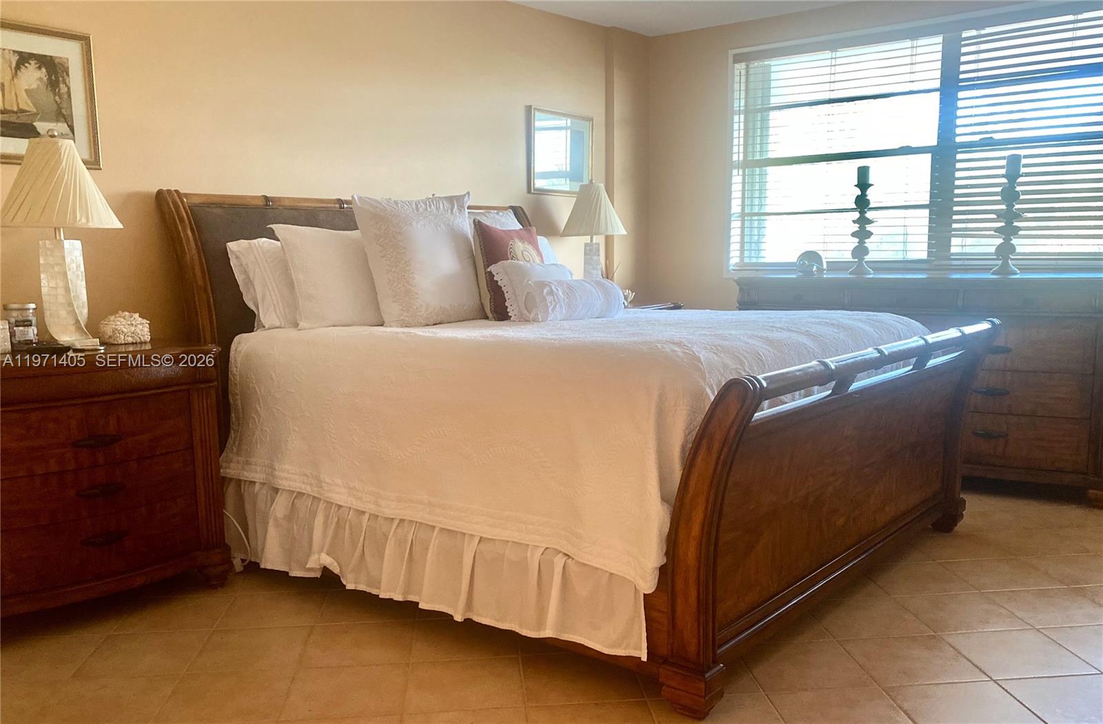 A bedroom features a wooden sleigh bed, tiled floors, and a window with blinds — 177 Ocean Lane Dr # 204, Key Biscayne FL 33149, KEY BISCAYNE, FL