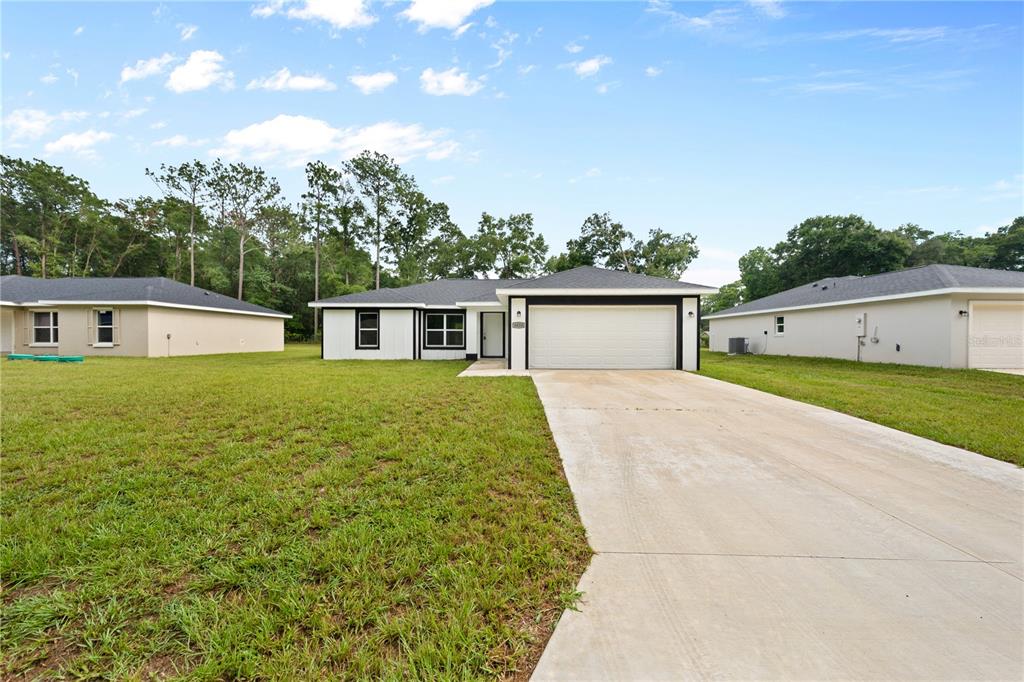 A single-story house with a white exterior, black trim, and a concrete driveway — 6026 NW 65TH STREET, OCALA, FL
