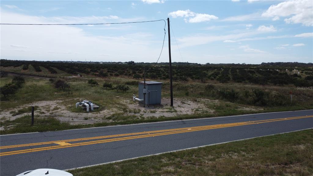 A utility shed and irrigation equipment sit beside a rural road near a large orchard — 3200 POWER LINE ROAD, AVON PARK, FL