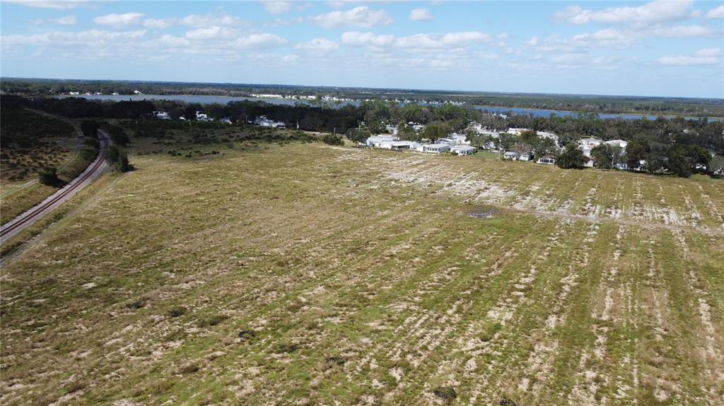 An aerial view shows a large, grassy vacant lot adjacent to railroad tracks and houses — 3200 POWER LINE ROAD, AVON PARK, FL