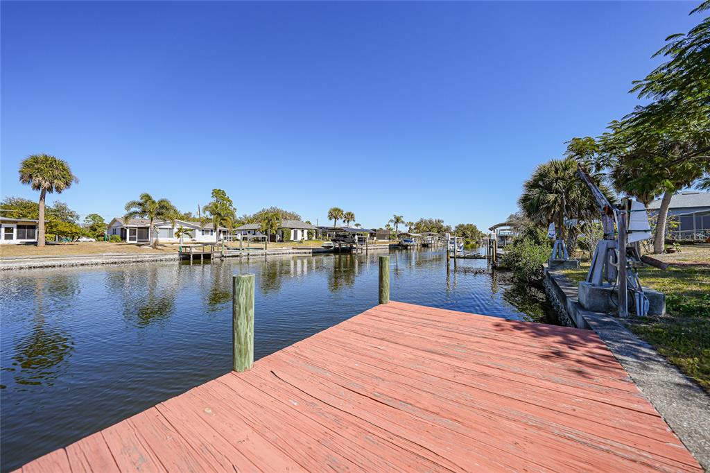 A wooden dock overlooks a narrow canal lined with houses and palm trees — 18366 BURKHOLDER CIRCLE, PORT CHARLOTTE, FL