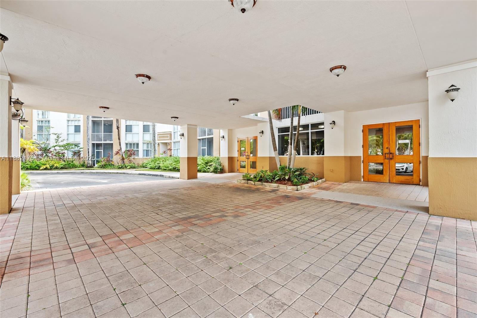 A paved porte-cochère leads to wooden double doors at the entrance of a building — 9805 NW 52nd St # 216, Doral FL 33178, DORAL, FL