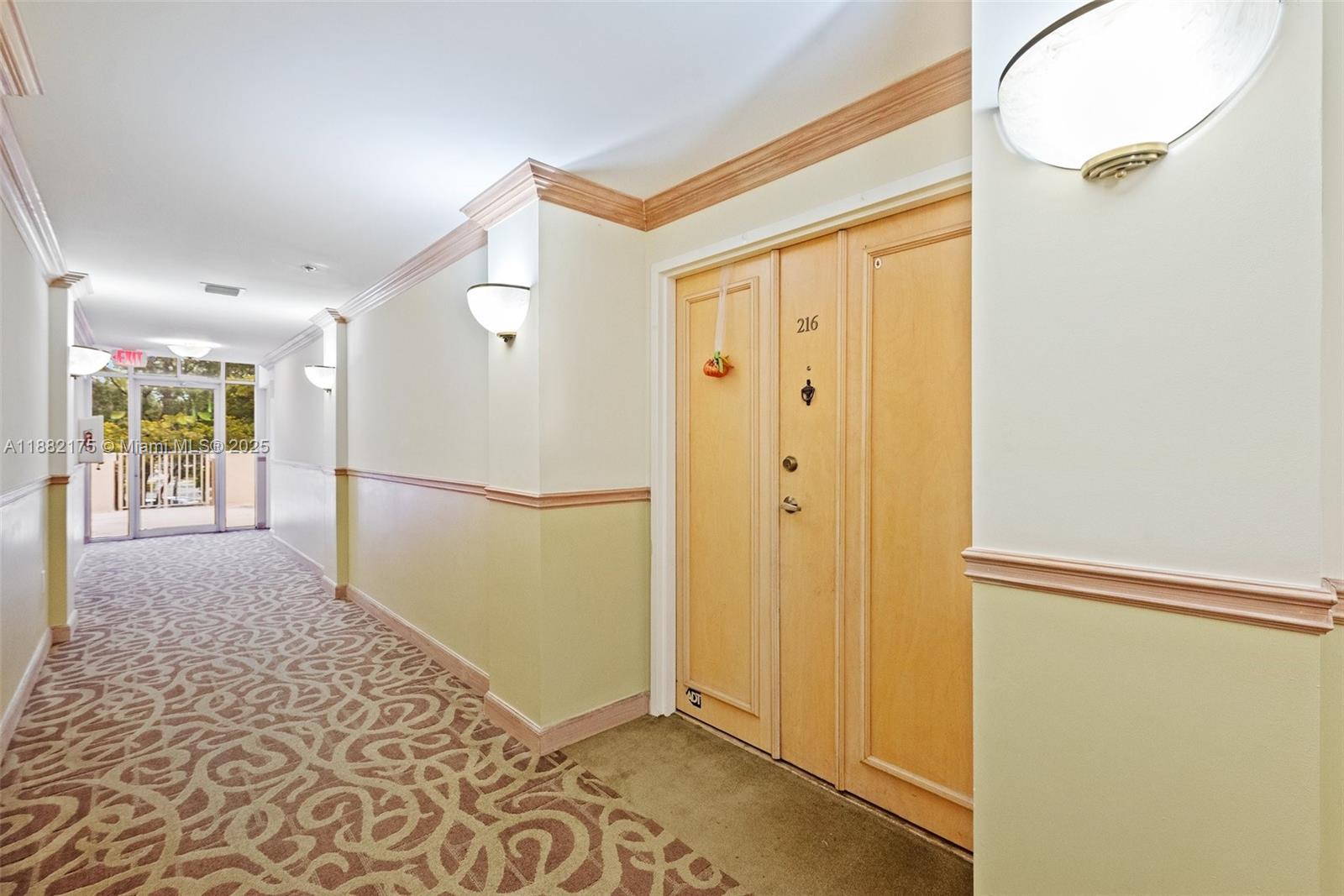 A hallway features patterned carpet, light-colored walls with chair rail molding, and a wooden door — 9805 NW 52nd St # 216, Doral FL 33178, DORAL, FL