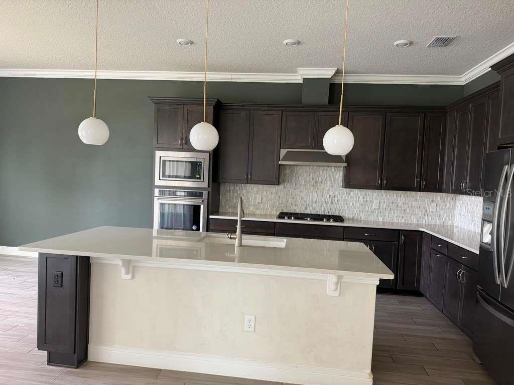 An open-concept living area features light wood-look tile flooring, shiplap walls, and sliding glass doors — 10732 PAHOKEE BEACH PLACE, ORLANDO, FL