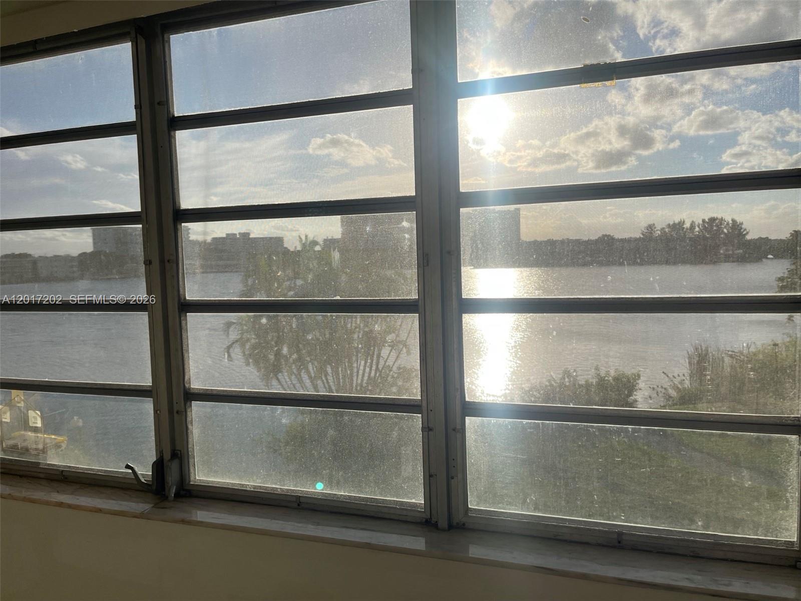 A view of a lake and distant buildings through a multi-pane window — 1660 NE 191st St # 1, Miami FL 33179, MIAMI, FL