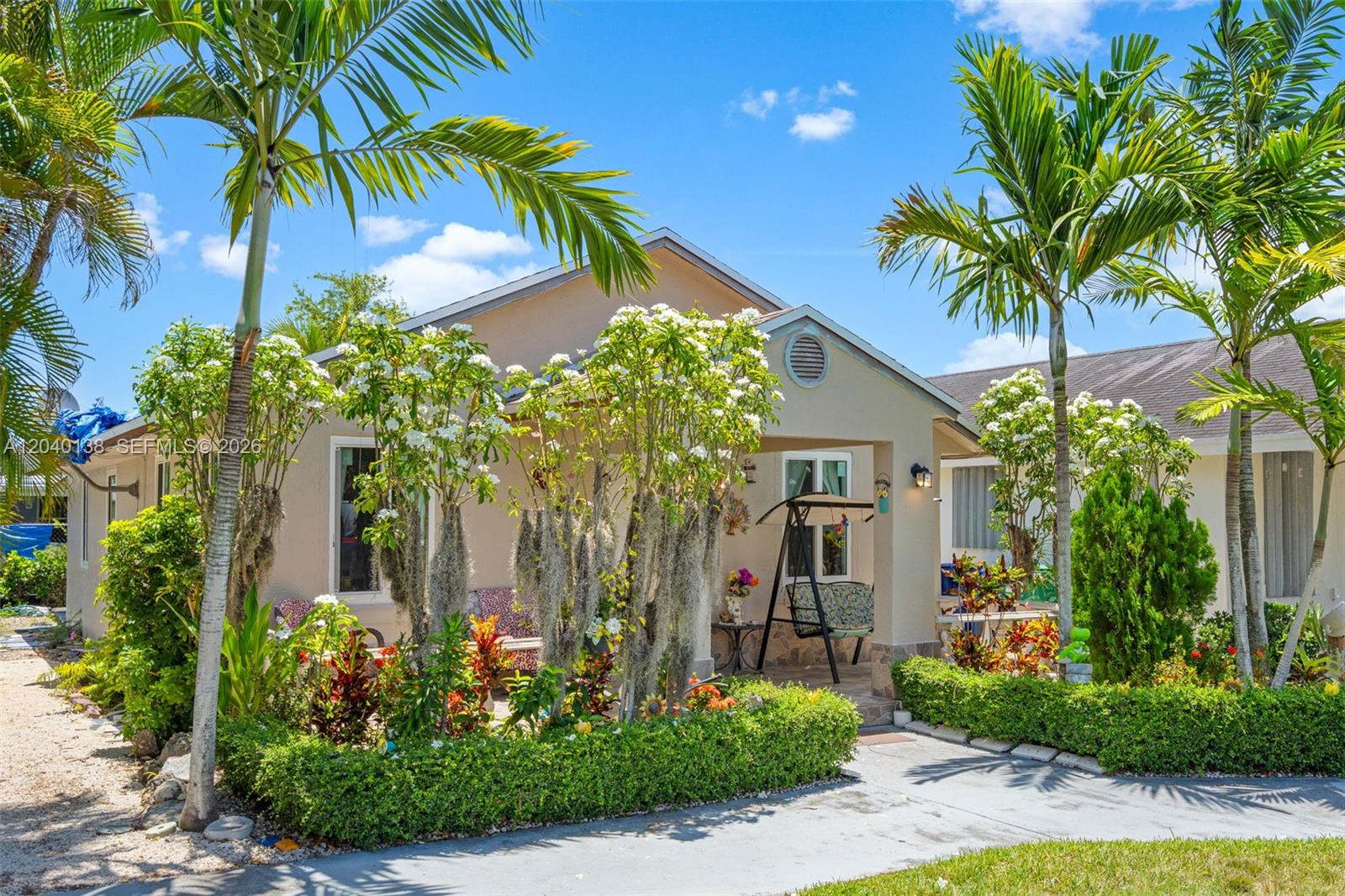 A single-story house with a covered porch, landscaping, and palm trees under a blue sky — 12243 SW 201st Ter, Miami FL 33177, MIAMI, FL
