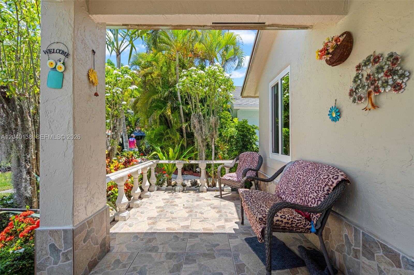 A covered patio features tiled flooring, a stone-style base, and two leopard-print chairs — 12243 SW 201st Ter, Miami FL 33177, MIAMI, FL