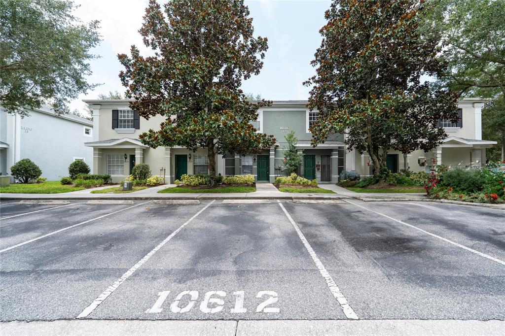 A two-story apartment building with parking spaces in the foreground and large trees — 10612 SAVANNAH WOOD DRIVE UNIT 86, ORLANDO, FL
