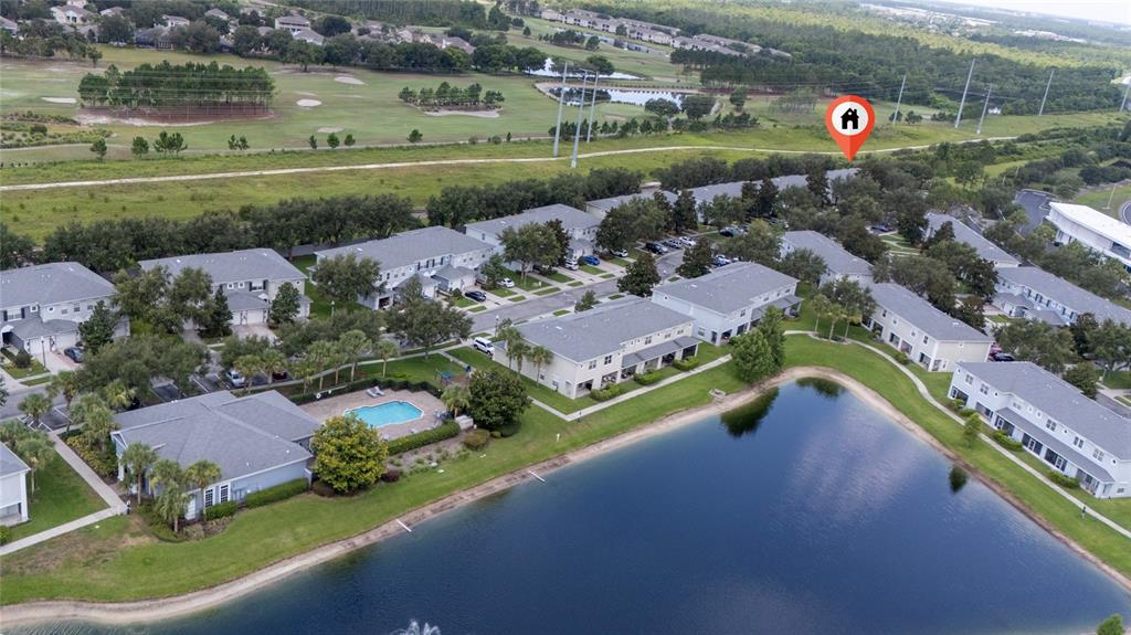 An aerial view shows a residential complex with townhomes, a swimming pool, and a pond — 10612 SAVANNAH WOOD DRIVE UNIT 86, ORLANDO, FL