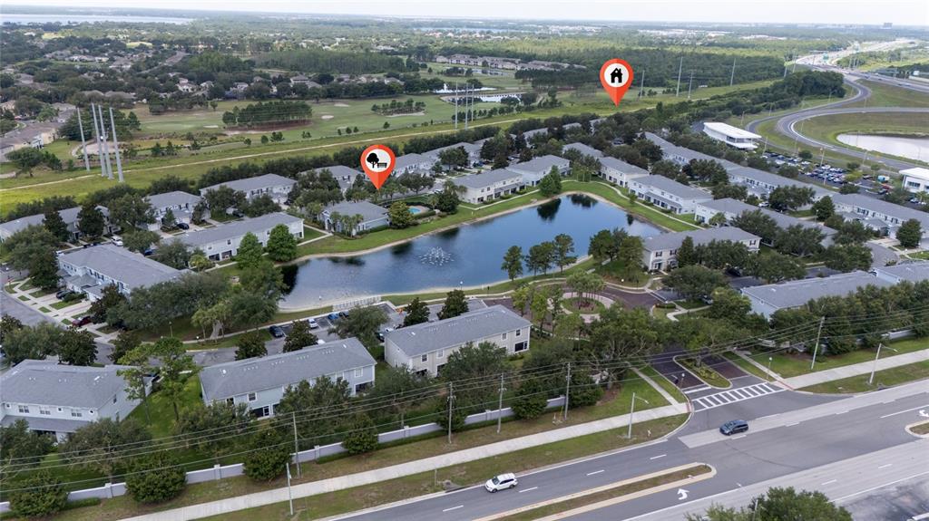 An aerial view shows a residential apartment complex surrounding a central pond with fountains — 10612 SAVANNAH WOOD DRIVE UNIT 86, ORLANDO, FL