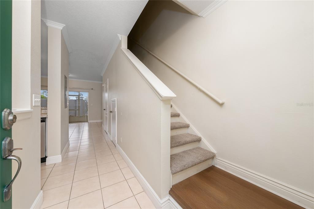 An entryway features tiled flooring, a carpeted staircase with a handrail, and a hallway view — 10612 SAVANNAH WOOD DRIVE UNIT 86, ORLANDO, FL
