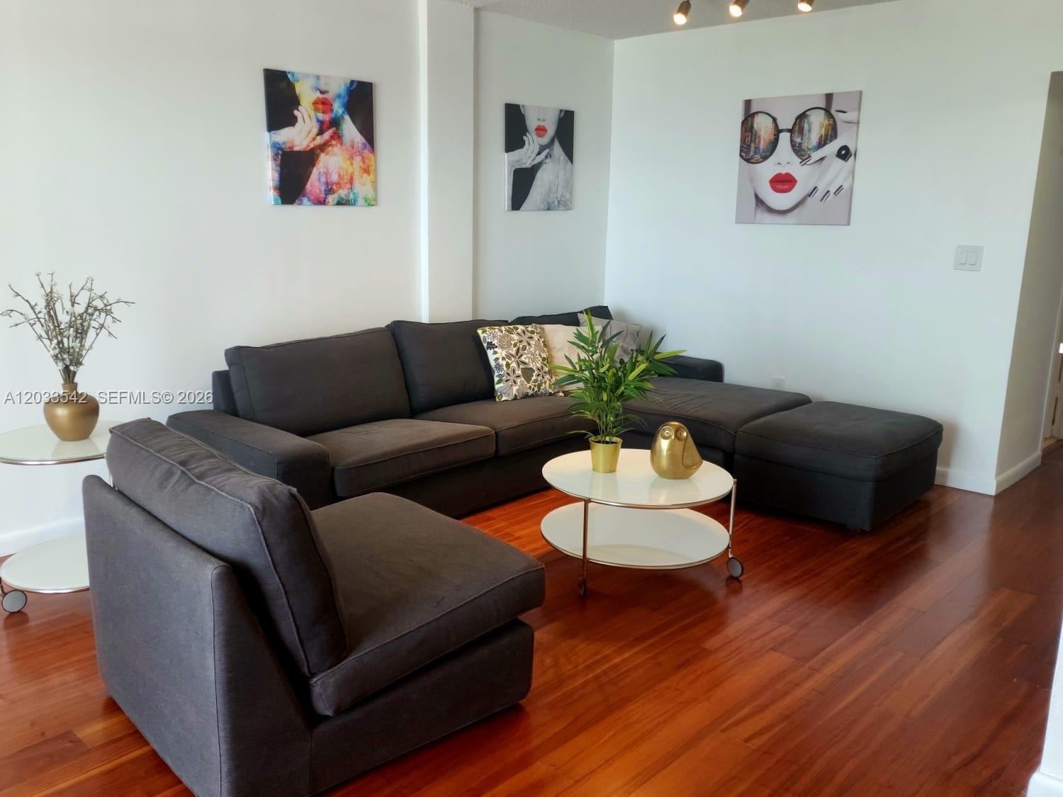 A living room features a dark gray sectional sofa, a matching armchair, and white tables — 1100 Alton Rd # 3C, Miami Beach FL 33139, MIAMI BEACH, FL