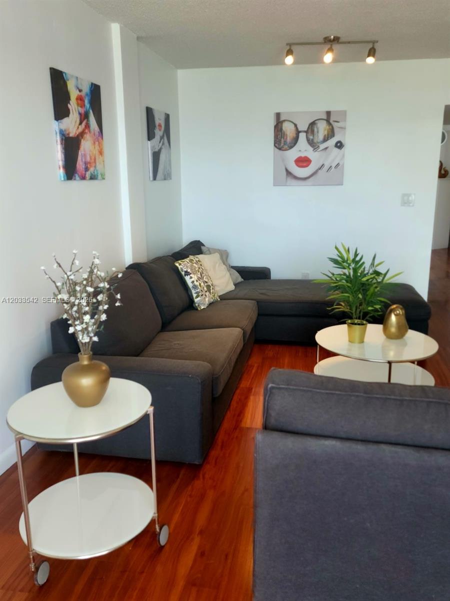 A living room features a dark sectional sofa, white round tables, and modern wall art — 1100 Alton Rd # 3C, Miami Beach FL 33139, MIAMI BEACH, FL
