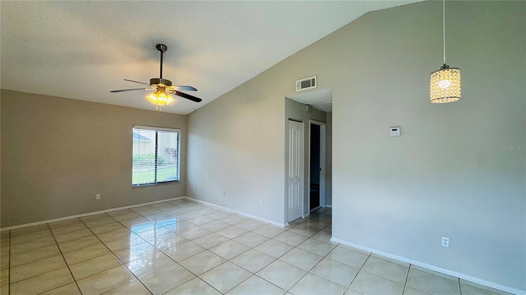 A room with beige walls, light-colored tile flooring, a vaulted ceiling, and a ceiling fan — 4415 PINEBARK AVENUE UNIT 48-4, ORLANDO, FL