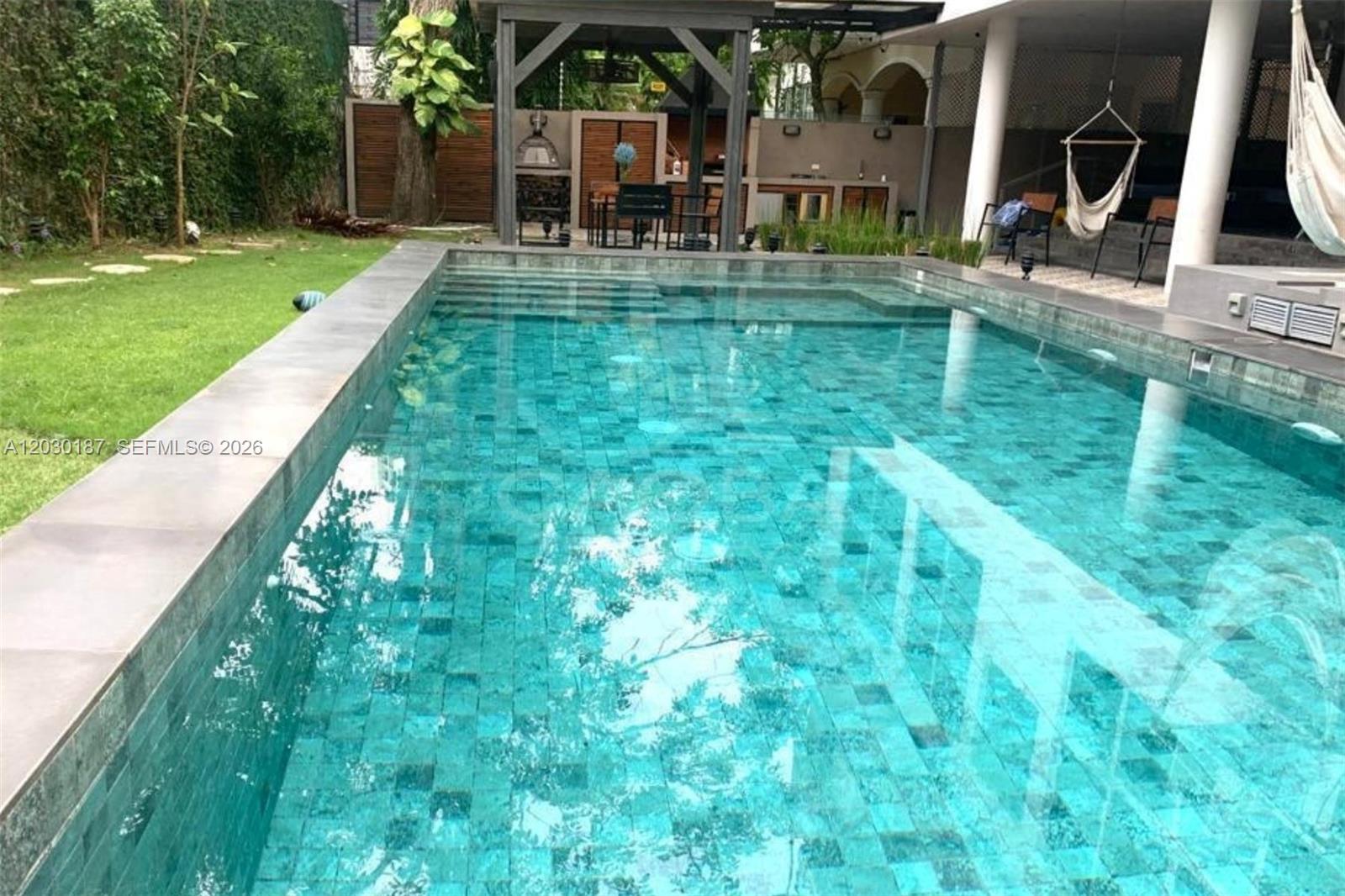 A rectangular swimming pool with blue mosaic tiles sits beside a grassy lawn and patio — 0 MARBELLA Panama Republic of Panama, FL, FL